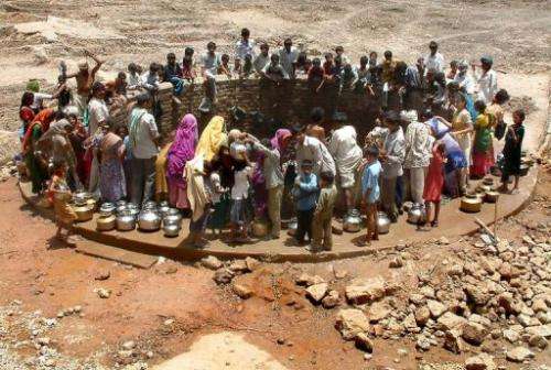 Indian villagers gather around a well to fill their pots with water during a drought in Gujarat on June 6, 2003