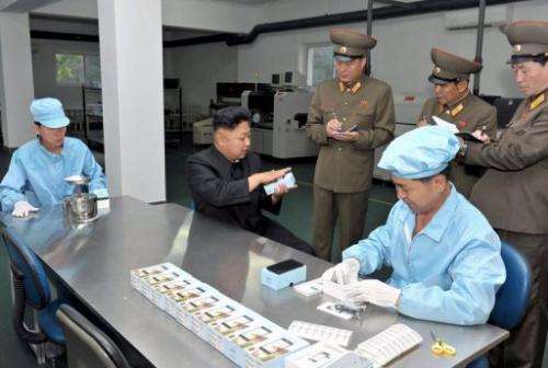 N.Korean leader Kim Jong-Un (C) inspects 'Arirang' smartphone at the May 11 factory, on August 11, 2013