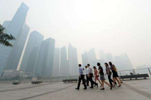 Office workers return from a lunch break in front of buildings blanketed by haze in Singapore on June 19, 2013