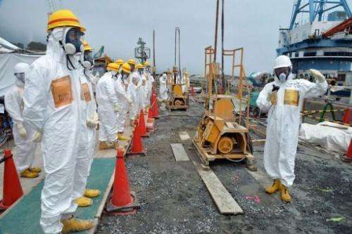 Officials inspect a construction site set up to prevent the seepage of contaminated water into the sea at Fukushima