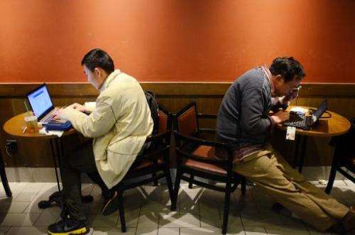 Two Chinese men use their laptop computers at a cafe in Beijing on November 2, 2012