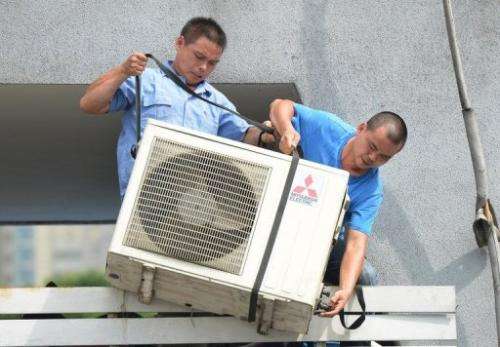 Workers install an air-conditioning unit at a food stall in Shanghai on July 2, 2013