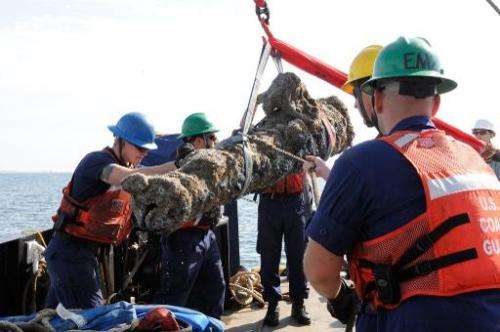 Members of the US Coast Guard and others raise a cannon from a sunken ship on October 28, 2013 off the coast of North Carolina