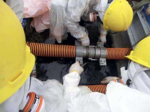 Image provided by TEPCO on October 9, 2013 shows workers checking pipe joints at a decontamination facility at the Fukushima nuc
