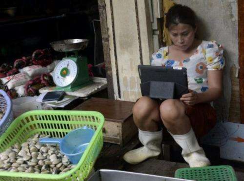 This picture taken on July 26, 2013 shows a seafood vendor using an iPad at her stand in a market in downtown Hanoi