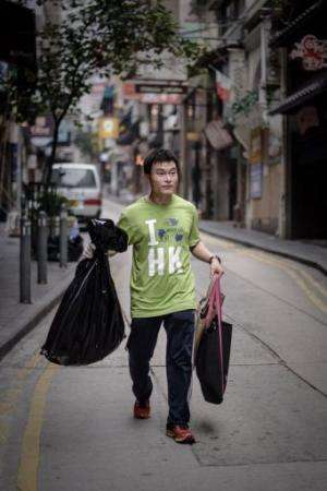 A member of the non-profit organisation Hong Kong Recycles carries bags filled with rubbish, on April 16, 2013