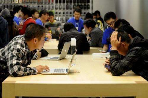 Customers look at Apple products in Apple's store at in Beijing on October 20, 2012