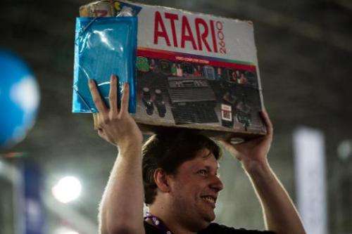 A man carries a box with an Atari game console as American Nolan Bushnell, founder of video game and home computer company Atari