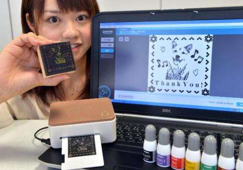 An employee of Japan's electronics maker Casio Computer displays a stamp maker &quot;Pomrie&quot; at the company's headquarters 