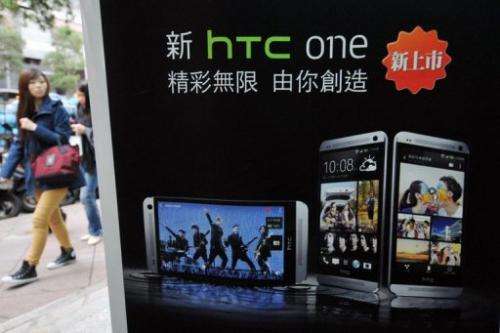 A woman walks past a HTC advertising in Taipei on May 2, 2013