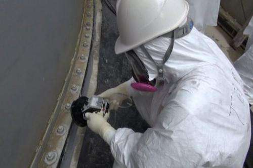 Image taken by TEPCO on September 4, 2013 shows a man checking radiation levels at a water tank at the Fukushima plant
