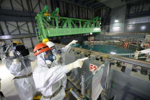 In this file photo, Fukushima Governor, Yuhei Sato (in orange helmet), inspects the spent fuel pool in the unit 4 reactor buildi