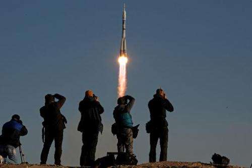 People take photographs as Russia's Soyuz TMA-11M spacecraft blasts off from the Russian leased Kazakh Baikonur cosmodrome on No