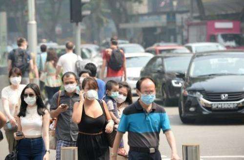 People wear face masks on Orchard Road in Singapore on June 22, 2013