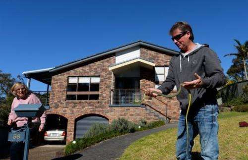 Snake handler Andrew Melrose holds a green tree snake outside a home in Sydney on August 5, 2013