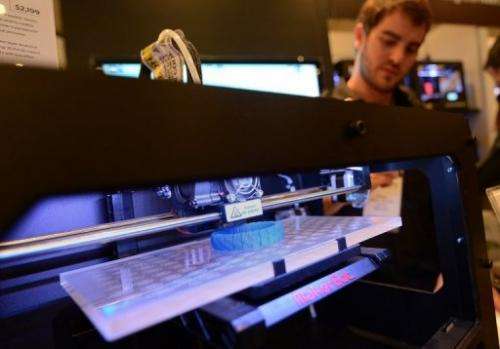 Visitors look at a 3D printer printing an object during an exhibition in New York on April 22, 2013