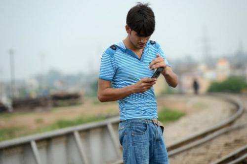 A man checks his messages alongside a railway track in Rawalpindi on September 10, 2013