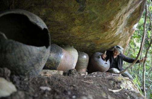 Archaeologist Tep Sokha studies bone from a jar in a cave at Phnom Pel, southwest of Phnom Penh, on March 24, 2013