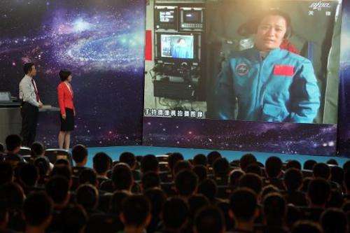 Chinese astrounaut, mission commander Nie Haisheng, speaks to students via video link, gathered at a school in Beijing, of June 