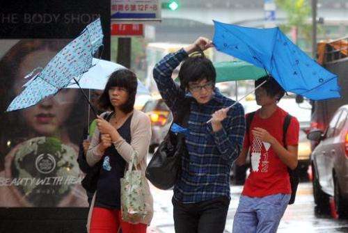 Pedestrians walk through strong winds and rain caused by Typhoon Fitow in Taipei on October 6, 2013