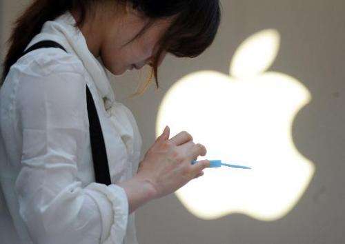 A woman uses her mobile phone outside an Apple store in Shanghai on May 7, 2012