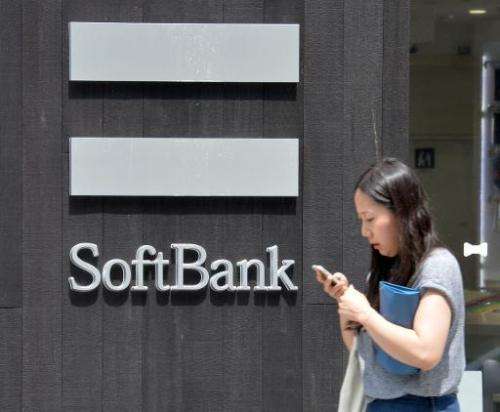 A woman uses her mobile phone outside a Softbank mobile phone shop in Tokyo on July 11, 2013