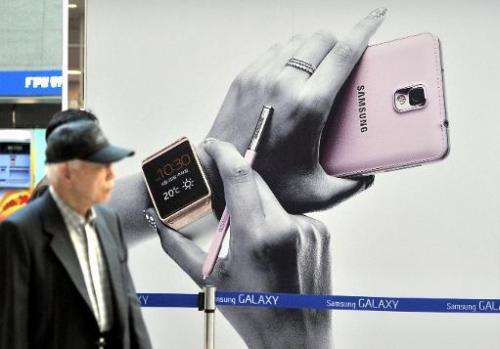 Pedestrians walk past a sign board advertising Samsung Electronics' Galaxy Note 3 smartphone at a railway station in Seoul on Oc