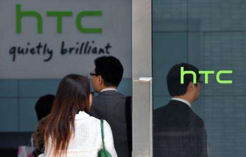 People walk past High Tech Computer Corp. (HTC) logos in Hsintien, Taipei on March 3, 2010