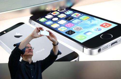 Apple CEO Tim Cook uses an iPhone to take a picture of customers waiting in front of an Apple store, September 20, 2013