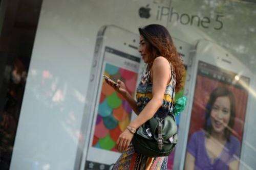 A woman looks at her mobile phone outside a store in Beijing on September 11, 2013