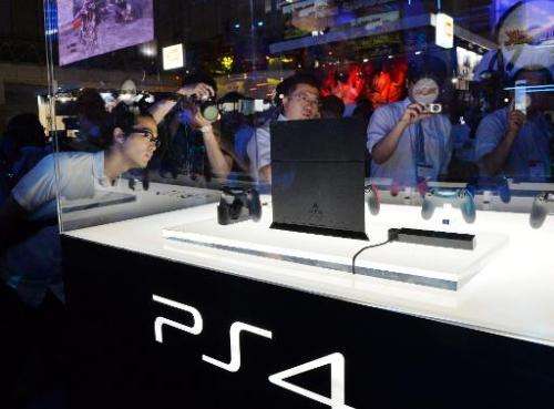 Visitors look at a display case containing Sony Computer Entertainment's PlayStation 4 at the Tokyo Game Show in Chiba, suburban