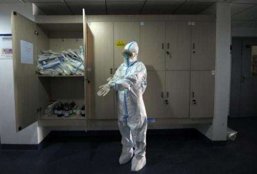 A Beijing Center of Disease Control staff member puts on a decontamination suit in their office in Beijing