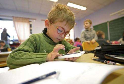 A boy writes on a smartphone during a lesson about Twitter in Seclin, France, on December 11, 2011