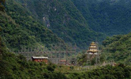 A Buddhist temple sits near an electricity grid main of the Chukha hydro power station, on May 29, 2013