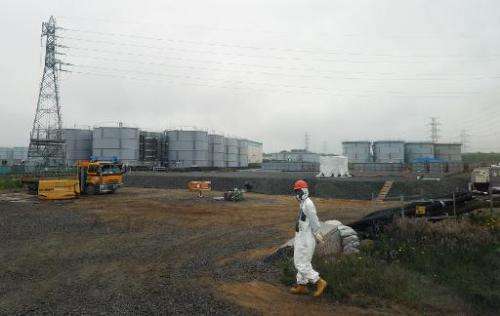 A construction worker walks near water tanks at the Fukushima nuclear plant in Fukushima prefecture, Japan on June 12, 2013