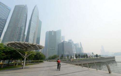 A cyclist rides along the pier in front of buildings blanketed by haze in Singapore on June 19, 2013