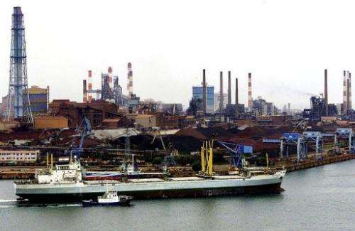 A freighter arrives at Kashima's main port with a metal factory seen in the background, on June  1, 2001