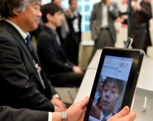 A Fujitsu engineer demonstrates how a smartphone that can take the pulse of a user works, on March 18, 2013