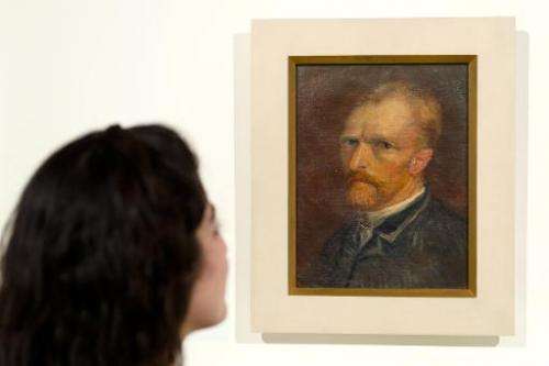 A gallery assistant poses with Vincent van Gogh, Self-portrait (December 1886-January 1887), during an exhibition preview in Lon
