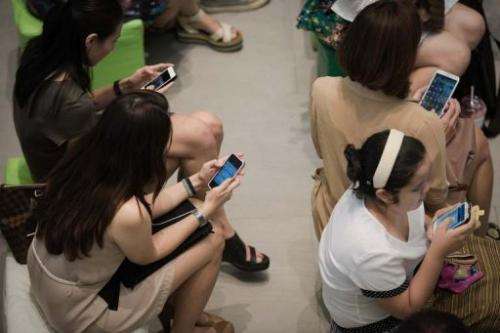 A group of people use their smartphones at a shopping mall in Bangkok, March 21, 2013