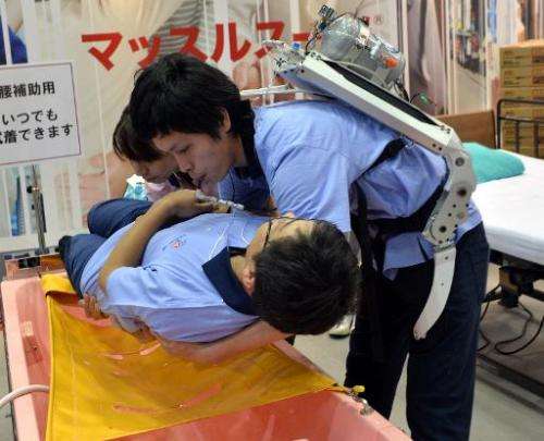 A Japanese elderly care company Asahi Sun Clean employee (top) wearing a power suit, called 'Muscle Suit,' lifts a fellow worker