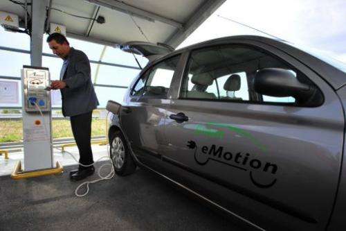 A man plugs an electric powered car to a charging station in Sofia on October 17, 2012