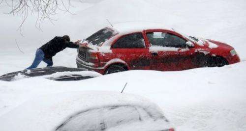 A man pushes a jammed car as heavy snow falls in Moscow, on March 15, 2013