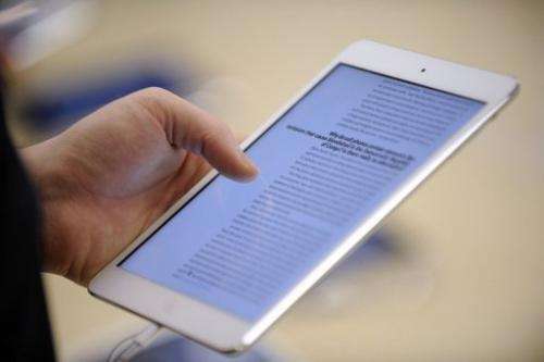 A man reads on a new iPad mini during the opening of a new Apple store in Saint-Herblain on November 15, 2012