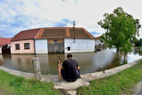 A man sits at a flooded street in Putim, near Pisek, Czech Republic, on June 5, 2013