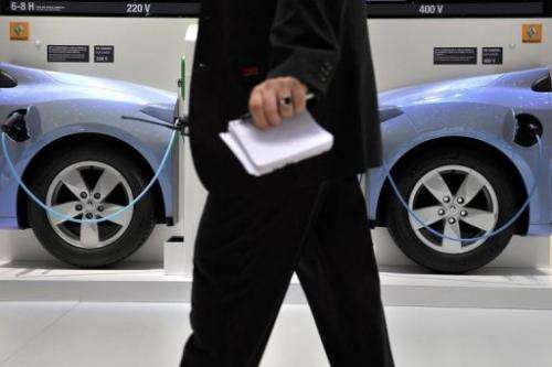 A man walks past a wall showing the electric car system at the French carmaker Renault's booth on March 2, 2011