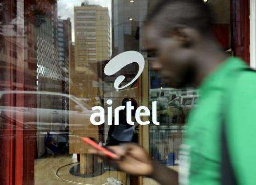 A man with a phone in hand walks past an'Airtel' logo in the Kenyan capital Nairobi on May 20, 2011