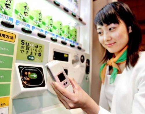 A model shows how to use a mobile phone equipped with a smartcard chip to pay a vending machine in Tokyo, 11 July 2005