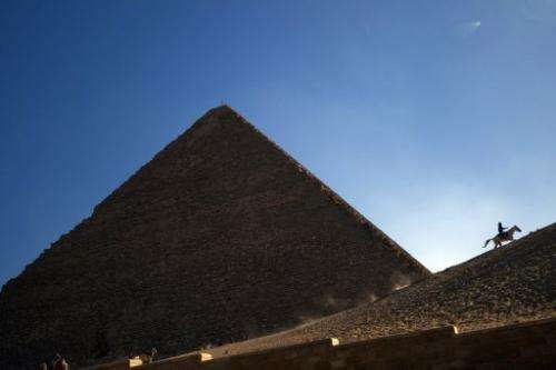 An Egyptian man rides a horse past one of the three Giza pyramids, south of Cairo, on December 22, 2012