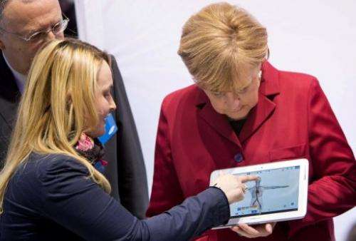 An employee demonstrates a Samsung tablet to Germany's Angela Merkel (R) at the CeBIT show in Hanover on March 5, 2013